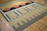Corner view of a Contemporary Kilim carpet, featuring gray and beige geometric patterns.