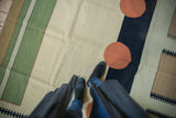 Abstract contemporary kilim featuring pale green stripe, madder red circles, charcoal patterns.