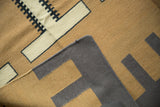 Kilim rug folded, ivory and coffee brown abstract pattern, pale charcoal navy underside, and original selvage.