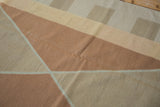 Modern kilim rug's geometric diamond pattern in copper, beige, and sand tones.