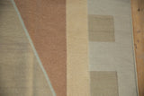 Corner detail of a modern geometric hand woven Indian Kilim rug in beige and copper tones.