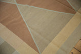 Close-up of a hand woven contemporary Kilim carpet, showing copper, beige, and pale gold Argyle diamonds.