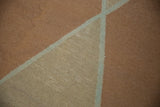 Hand-woven kilim texture showing geometric diagonal lines in copper, beige, silver.