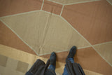 Close-up of the vintage kilim carpet's modern argyle pattern in copper and sand.