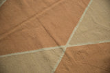 Argyle-inspired geometric diamond pattern of pale copper, sand, and ecru on contemporary Kilim.