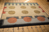 Corner of a contemporary kilim rug with jet black border and pale terracotta rust circle.