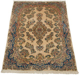 High-angle view of a vintage Kerman carpet with an ivory floral field and rich blue border.