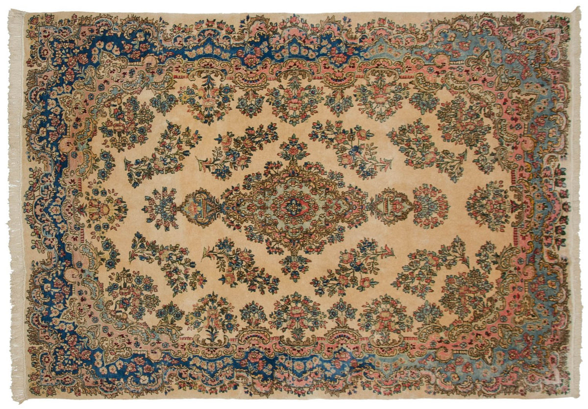 Vintage Kerman carpet with a floral medallion, ivory field, and sapphire blue and rose border.