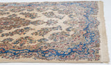 Angled view of the Kerman carpet's even pile, Rococo border, and clean fringe.
