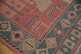 Indian Soumac carpet corner with geometric patterns in dusty rose, sea foam green, and fringe.