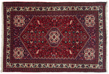 Geometric diamond medallion and playful motifs on the cherry red field of a vintage Abadeh rug.