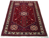 Angled view of a vintage Abadeh rug's geometric pattern and plush cherry red pile.