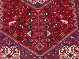Dense cherry red pile with playful bird and plant motifs on a vintage Abadeh rug.