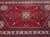 Crisp hand-knotted bird and floral motifs on the cherry red field of a vintage Abadeh rug.