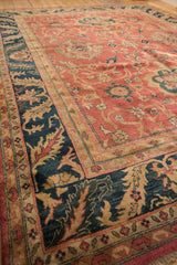 Angled view of a vintage Agra carpet's navy blue border with bold sand-colored leaf motifs.