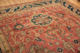 Angled view of a vintage Agra carpet's copper floral field and deep navy border.