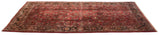 Angled view of a vintage Sarouk carpet showing floral bouquets on a soft ruby red field.