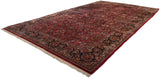 Angled perspective of a vintage Sarouk carpet with dense floral sprays on a ruby red field.