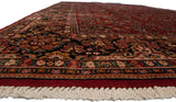 Low angle view along the plush pile of a vintage Sarouk carpet, showing the floral border and corner fringe.
