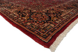 Corner of a vintage American Sarouk carpet showing its plush full pile, floral border, and clean fringe.