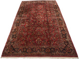 Angled view of a vintage Sarouk carpet with allover floral sprays on a ruby red field.