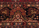 Gem-tone floral bouquets on the navy blue border of a vintage hand-knotted Sarouk carpet.