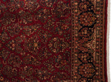 Detailed floral sprays on the ruby red field and navy blue border of a hand-knotted Sarouk carpet.