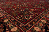 The plush, ruby red pile and detailed floral corner of a vintage American Sarouk carpet.