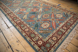 Angled corner view of a vintage Armenian rug with a layered floral border and cream fringe.