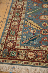 Corner view of an Armenian rug runner with its red floral border, denim blue field, and cream fringe.