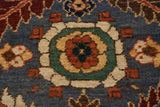 A top-view floral design motif in terracotta, gold, and green on the rug's blue wool pile.