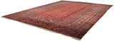 Angled view of a vintage fine Bokhara carpet showing its repeating red gul pattern and ivory fringe.