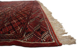 Detailed view of the vintage Bokhara carpet's edge, showing the intact selvage, plush red pile, and ivory fringe.