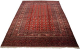 Angled view of a vintage Bokhara carpet highlighting the sheen across its cherry red gul pattern.