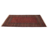 Fine vintage Bokhara carpet viewed from an angle, highlighting its plush, red pile and geometric guls.