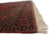 Angled view of a vintage Bokhara carpet's lustrous wool pile, detailed geometric border, and ivory fringe.