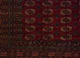 Detailed corner of a fine Bokhara carpet showing the plush pile and geometric gul medallions.