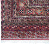 Vintage Bokhara rug corner, cherry red geometric border, intact selvage, and white fringe.