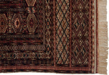 Detailed view of a Bokhara carpet's geometric borders, intact side selvage, and plush ivory fringe.