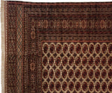 Corner detail of a fine Bokhara rug showing intricate geometric borders and rust gul medallions.