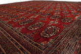 Fine gul medallions and lustrous red pile of a vintage Bokhara carpet from a low perspective.
