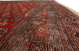 Lustrous wool pile and detailed borders of a vintage Bokhara carpet shown from a low angle.