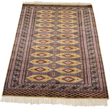 Angled perspective of a vintage Pakistani Turkmen rug showing its detailed borders and geometric guls.
