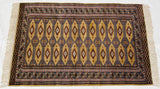 Vintage Pakistani rug displaying rows of geometric guls and intricate borders on a saffron gold field.