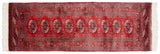 Vintage Bokhara rug corner detail: cherry red gul medallions, navy accents, ivory fringe.