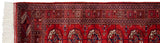Detailed view of Bokhara rug runner's white fringe, red selvage, and cherry red gul medallions.
