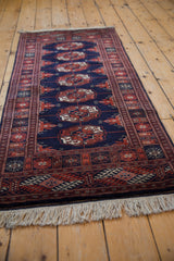 Repeating Bokhara gul medallions in rich navy and deep rust tones.