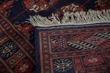 Vintage Bokhara rug runner's detailed navy, rust, and ivory geometric gul pattern and fringe.
