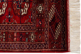 Vintage Bokhara rug showing plush cherry red 'gul' motifs, rich navy border, and intact ivory fringe.