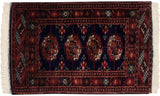 Vintage Pakistani Bokhara rug with repeating rust and ivory gul medallions on a deep navy blue field.